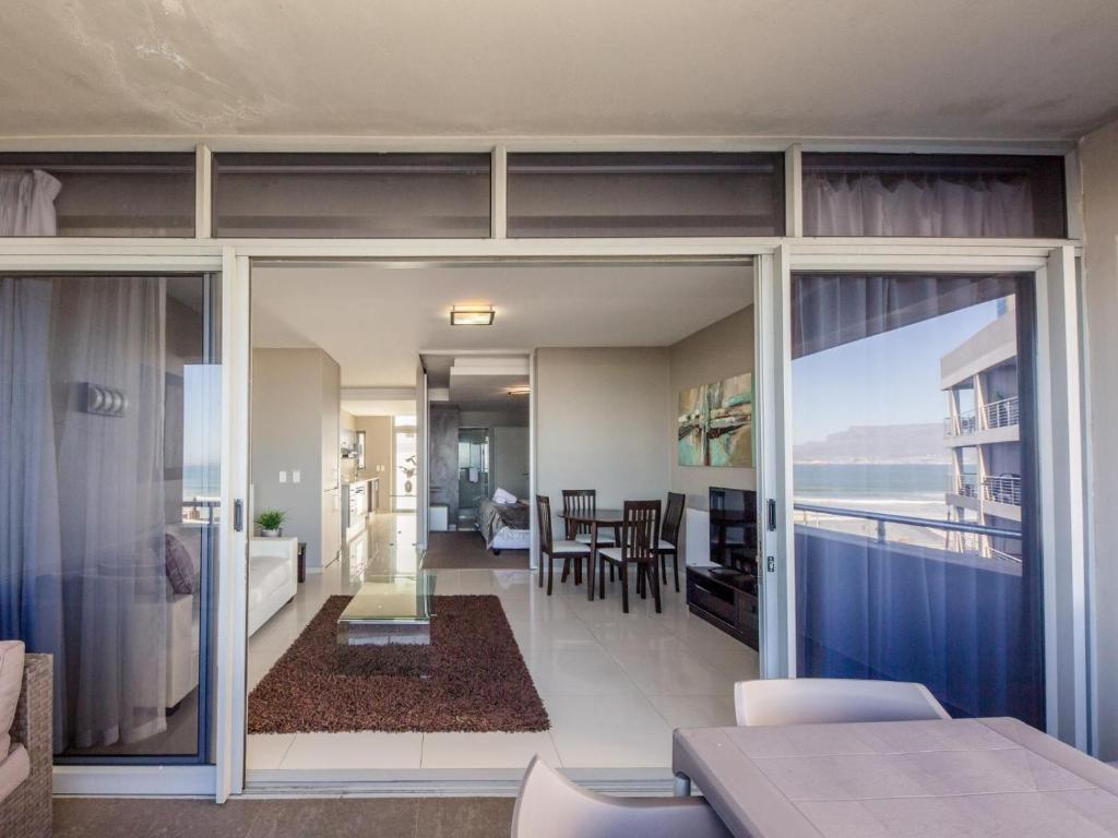 ein Wohnzimmer und ein Esszimmer mit Meerblick in der Unterkunft Infinity Self Catering Apartments in Bloubergstrand