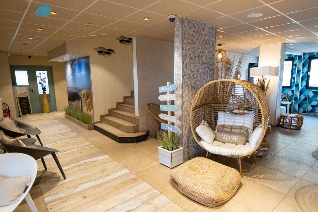 a lobby with a wicker chair and a staircase at The Originals Boutique, Hôtel Neptune, Berck-sur-Mer in Berck-sur-Mer