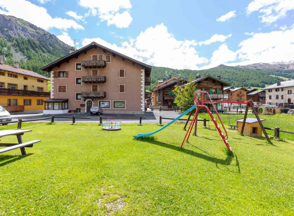 a playground with a slide in the grass in front of a building at Residence Adele in Livigno