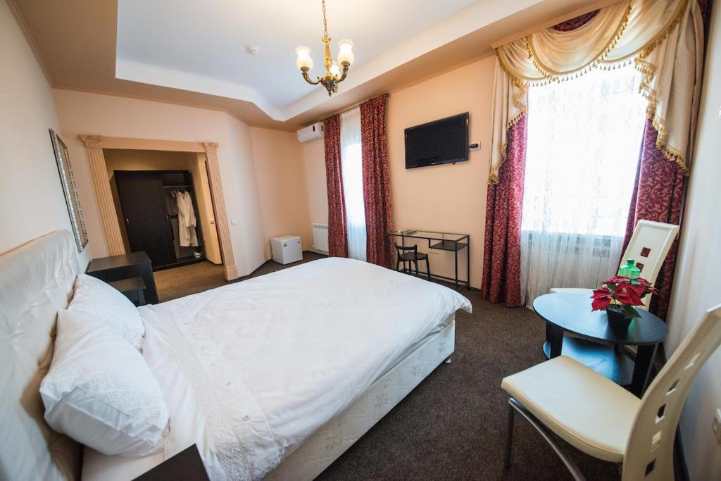 1 dormitorio con cama blanca, mesa y ventana en Paradise Hotel, en Goryachiy Klyuch