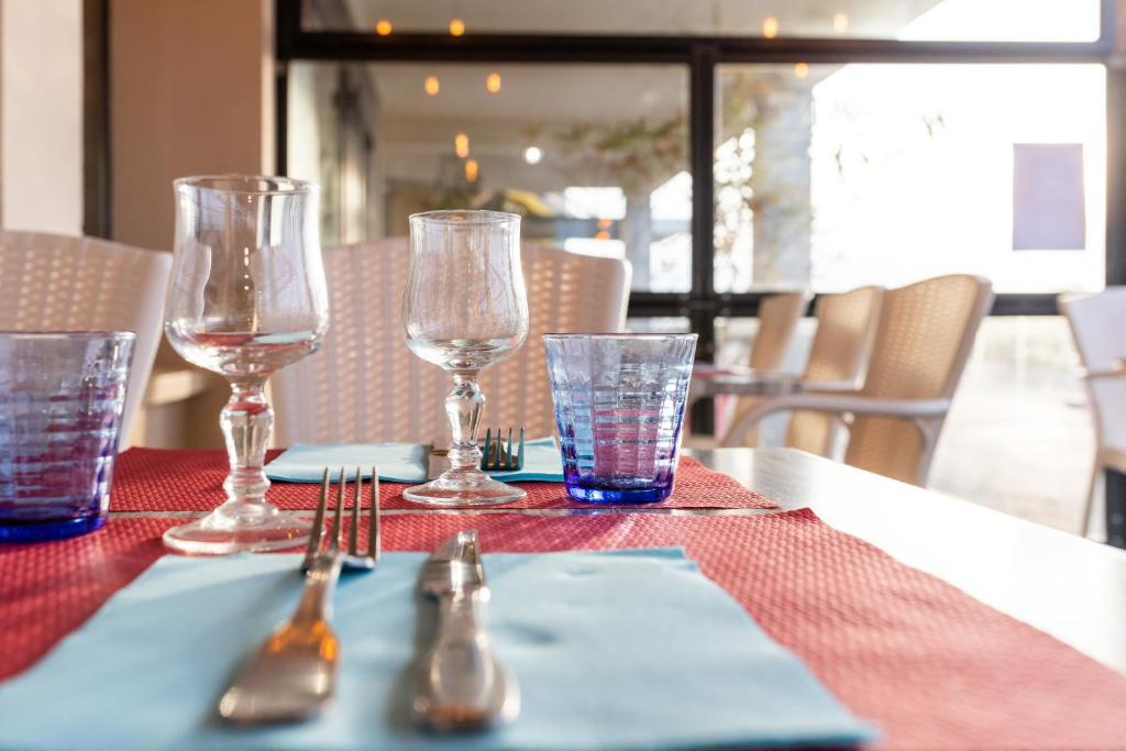 a table with glasses and utensils on a table at The Originals Boutique, Hôtel Neptune, Berck-sur-Mer in Berck-sur-Mer