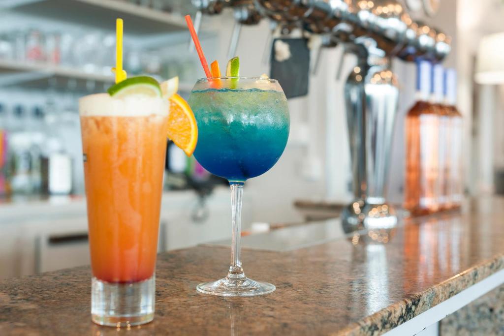 two cocktails sitting on a counter in a bar at The Originals Boutique, Hôtel Neptune, Berck-sur-Mer in Berck-sur-Mer