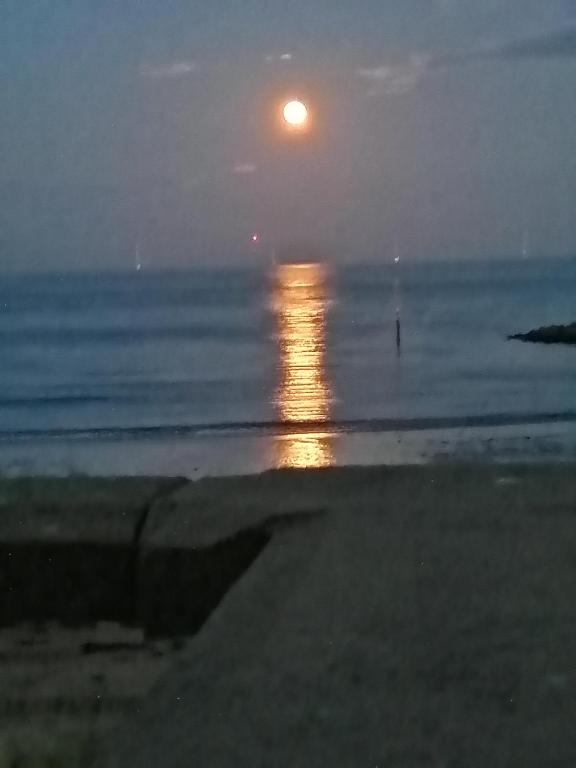 a full moon rising over the ocean at the beach at Captains Lodge in Newbiggin-by-the-Sea