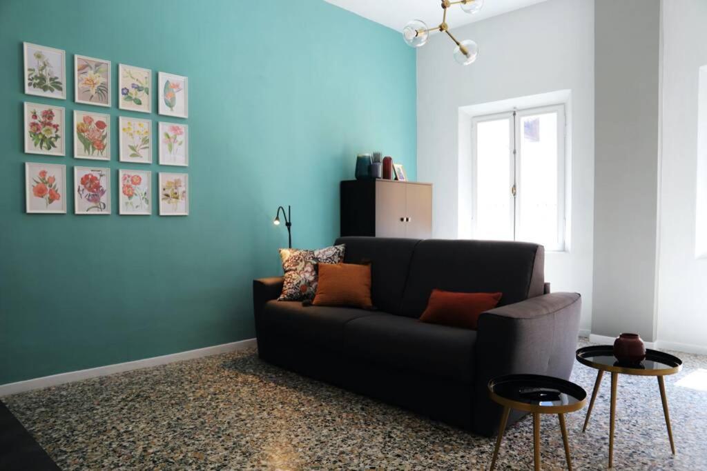 un salon avec un canapé noir et un mur bleu dans l'établissement La casa in via della Torre, à Modène