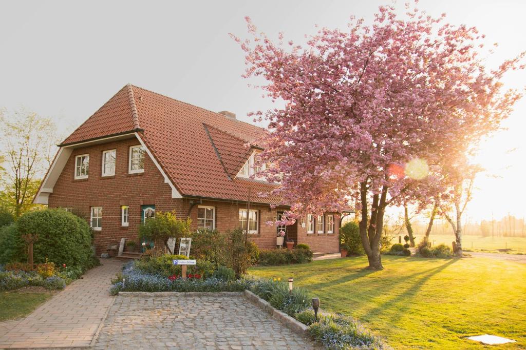 a house with a flowering tree in the yard at Ferienhaus Ostebogen in Hechthausen
