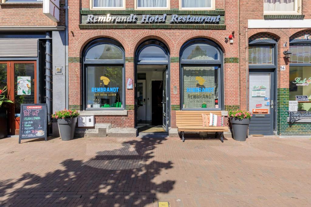 a building with a bench in front of a store at City Hotel Rembrandt in Leiden
