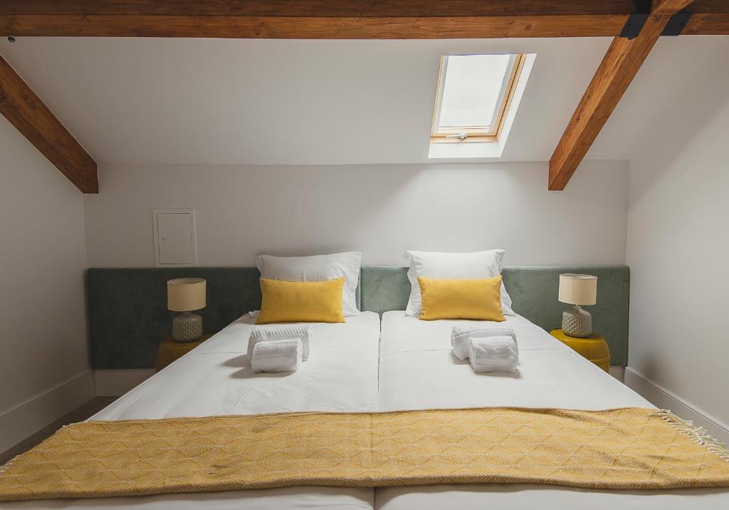 una camera da letto con un grande letto bianco con cuscini gialli di Vibrant Porto Apartments - Heroismo's Metro a Porto