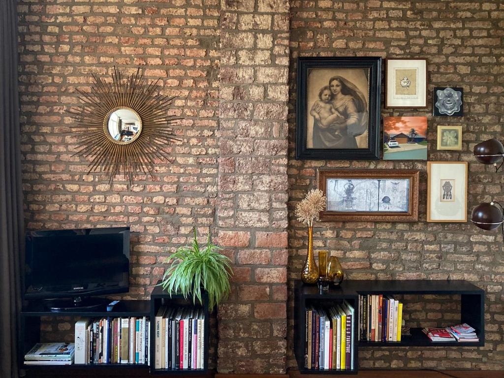 een kamer met een bakstenen muur met een tv en boeken bij Besselaar Apartments in Maastricht