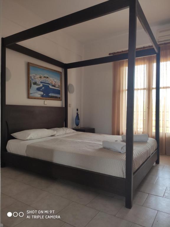 1 dormitorio con 1 cama grande con marco de madera en Elsa Apartments, en Pefkohori