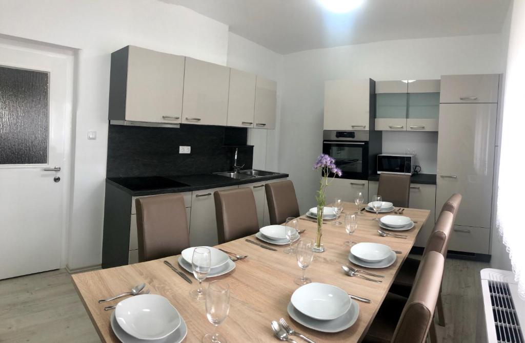 a kitchen with a wooden table with plates and wine glasses at Apartments Andrej in Ptuj