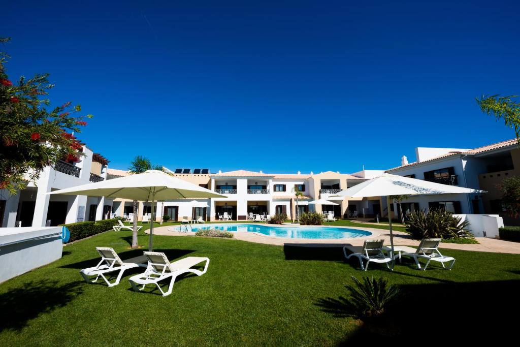 a resort yard with chairs and a swimming pool at Sagres Time Apartamentos in Sagres