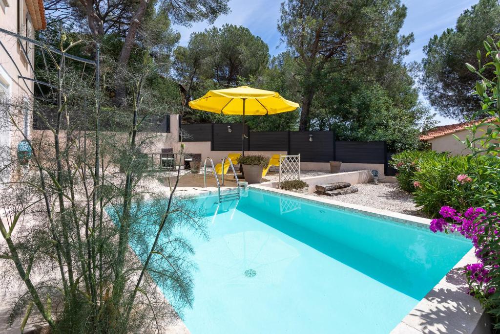 a swimming pool with a yellow umbrella next to a house at Les Bastides du Haut Para in Bormes-les-Mimosas