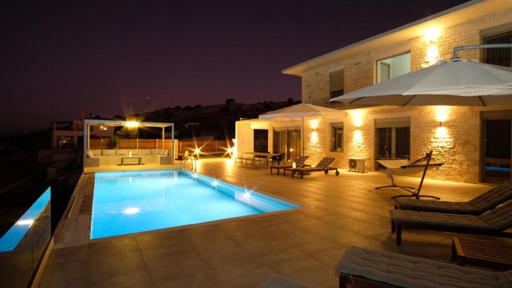 a swimming pool in front of a house at night at Eva Villas East, with infinity pool & and panoramic sea view in Gerani