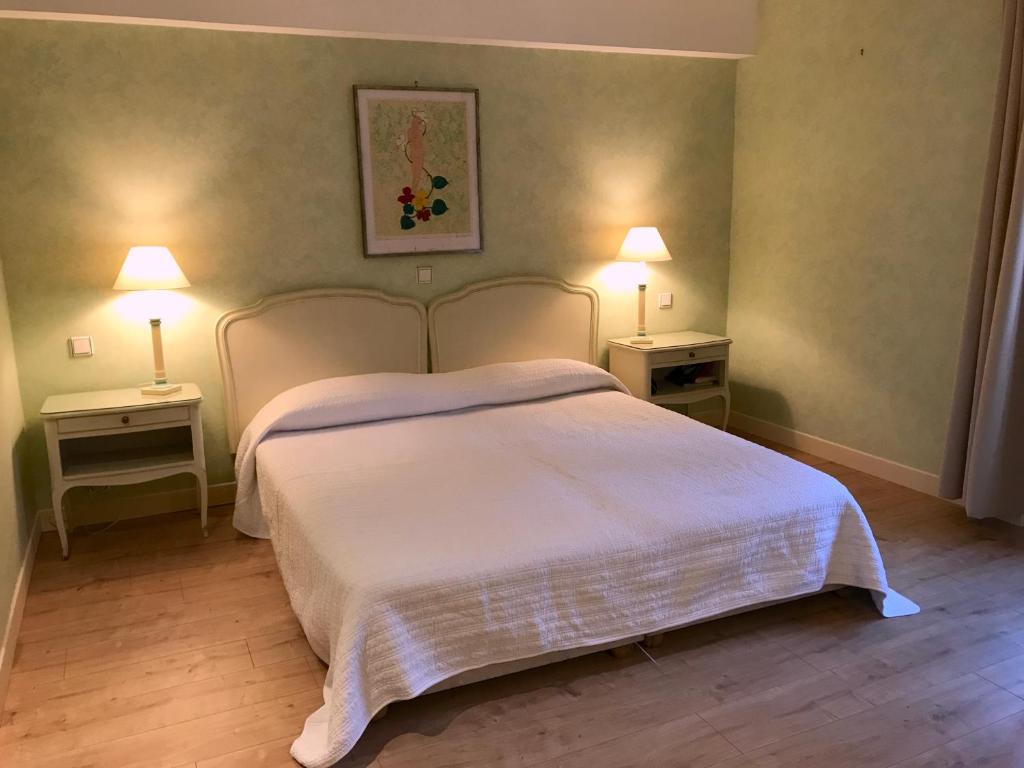 a bedroom with a white bed with two night stands at Ancienne Auberge des Brizards - Morvan (14 personnes) in Quarré-les-Tombes