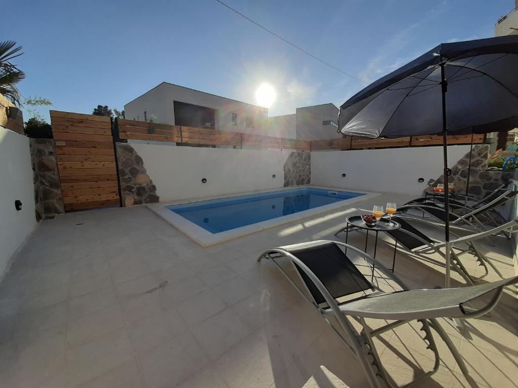 una piscina con sillas y sombrilla en Apartman Manuela, en Šibenik