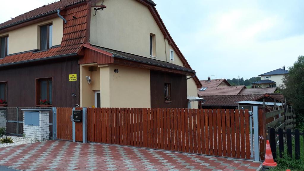 a house with a wooden fence and a brick driveway at Apartmán u potoka in Sadov