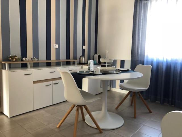a kitchen with a table and white chairs in a room at B&B Campitur in Campomarino
