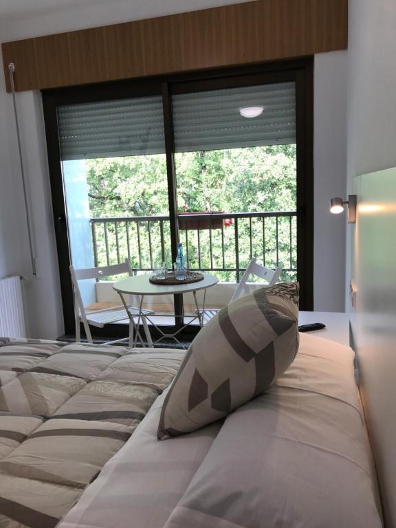 1 dormitorio con cama, mesa y balcón en El Malecon en Sarria