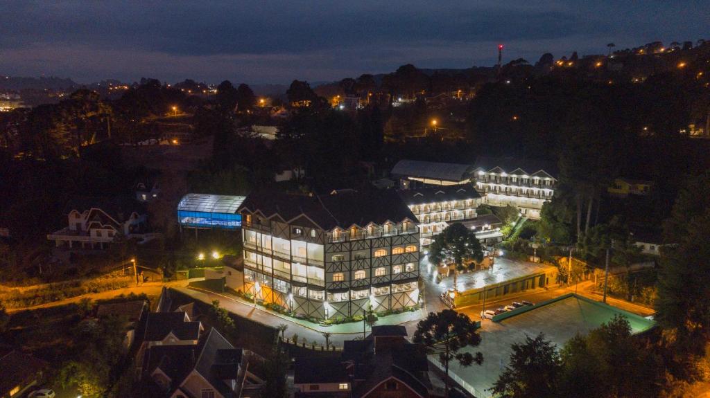 a large building with a pool in front of it at night at Hotel Leão da Montanha in Campos do Jordão