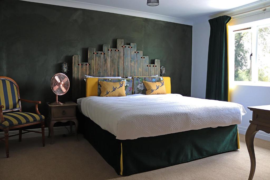 a bedroom with a bed with a large headboard at Shillingford Bridge Hotel in Wallingford