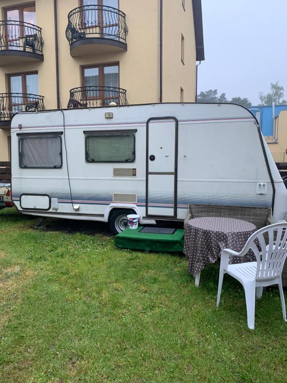 a white caravan parked next to a table and a chair at Tififi przyczepa in Pobierowo