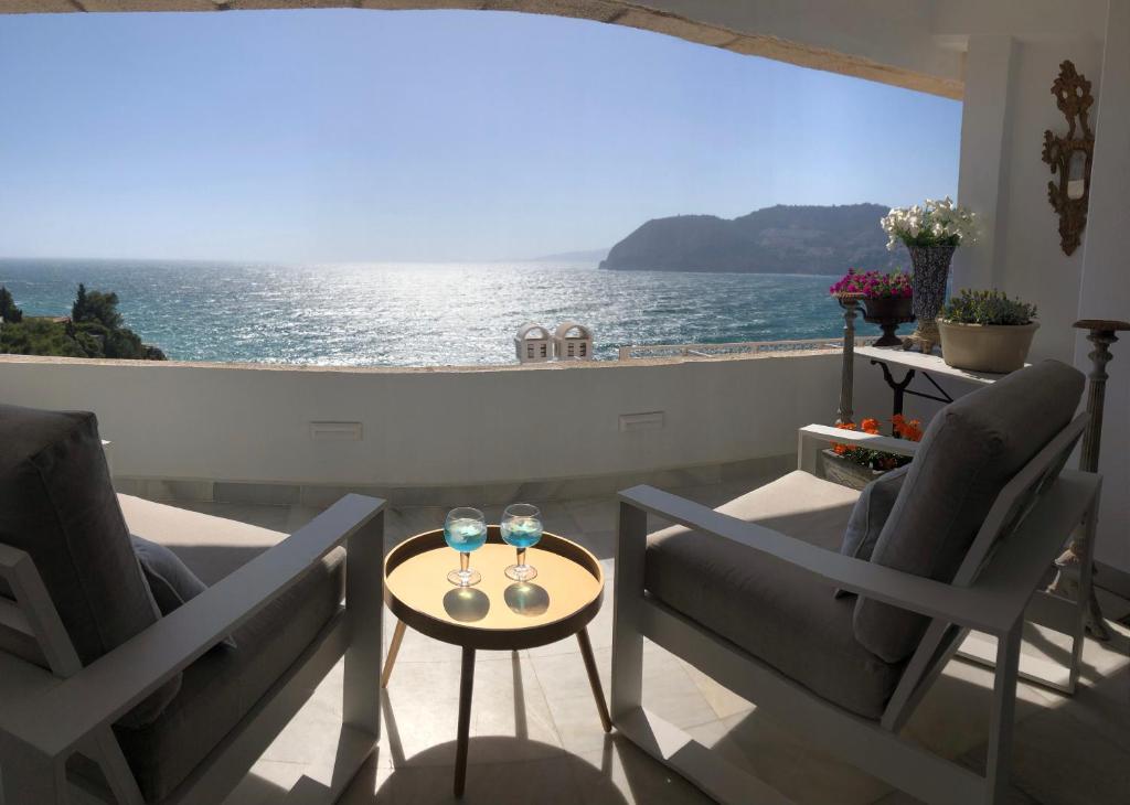 a balcony with two chairs and a table with wine glasses at La Herradura 3 bedroom apartment in La Herradura
