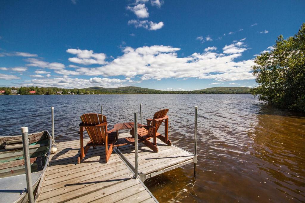 dos sillas y una mesa en un muelle en un lago en Le Gite Du Hu-Art, en Quebec