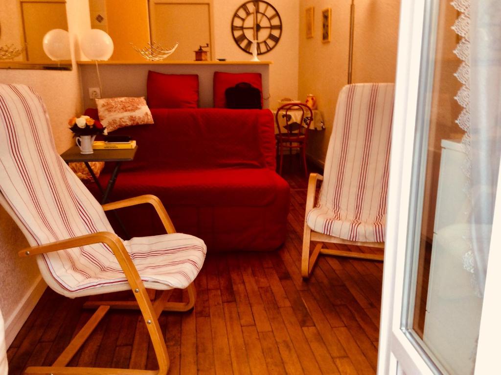 トゥルヴィル・シュル・メールにあるAgréable appartement dans le vieux Trouvilleのリビングルーム(赤いソファ、椅子2脚付)