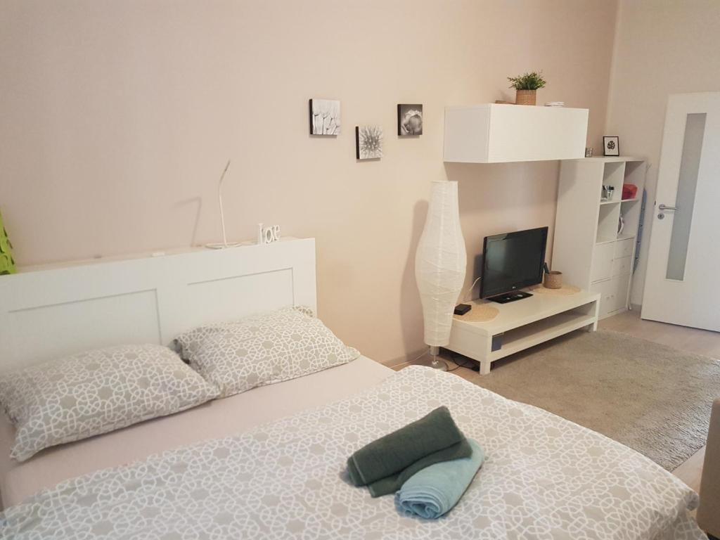 a white bedroom with a bed and a television at KaVi apartments #2 in Plzeň