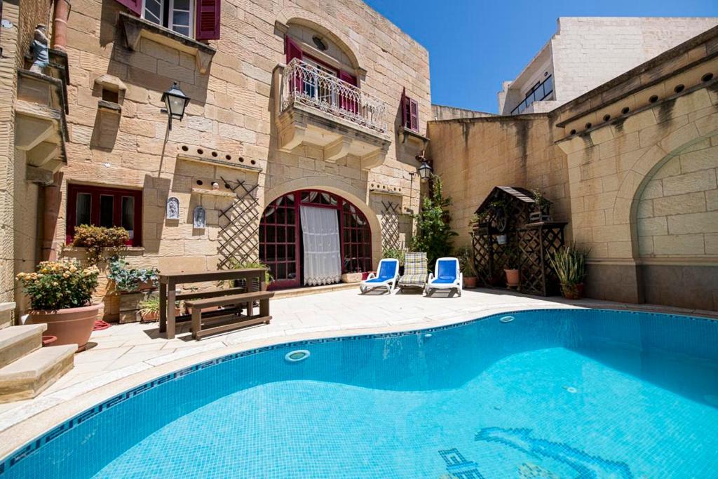 - une piscine avec 2 chaises bleues à côté d'un bâtiment dans l'établissement Ta' Kullarina Farmhouse with Private Pool in Island of Gozo, à Żebbuġ