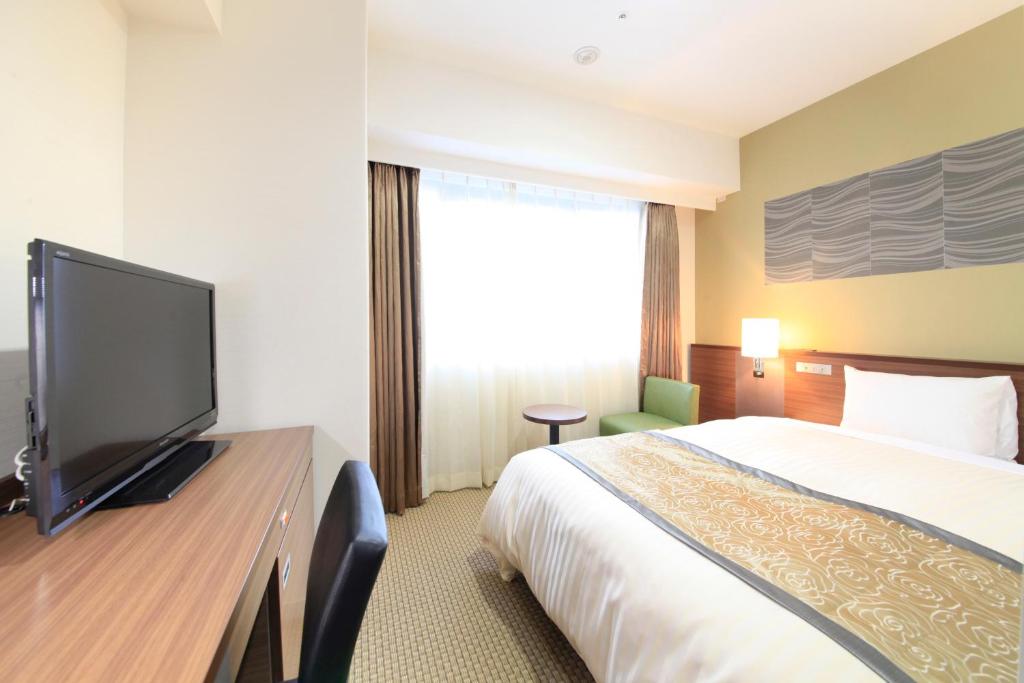 a hotel room with a bed and a flat screen tv at Vessel Inn Sapporo Nakajima Park in Sapporo