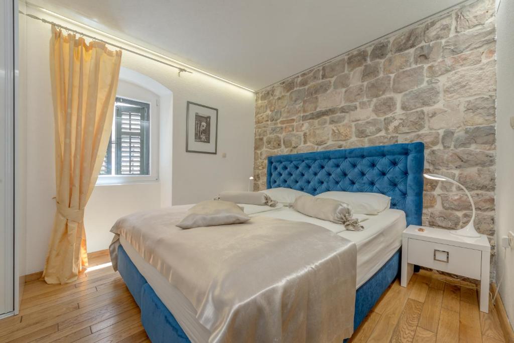 een blauw bed in een kamer met een stenen muur bij Guesthouse Imperator in Split