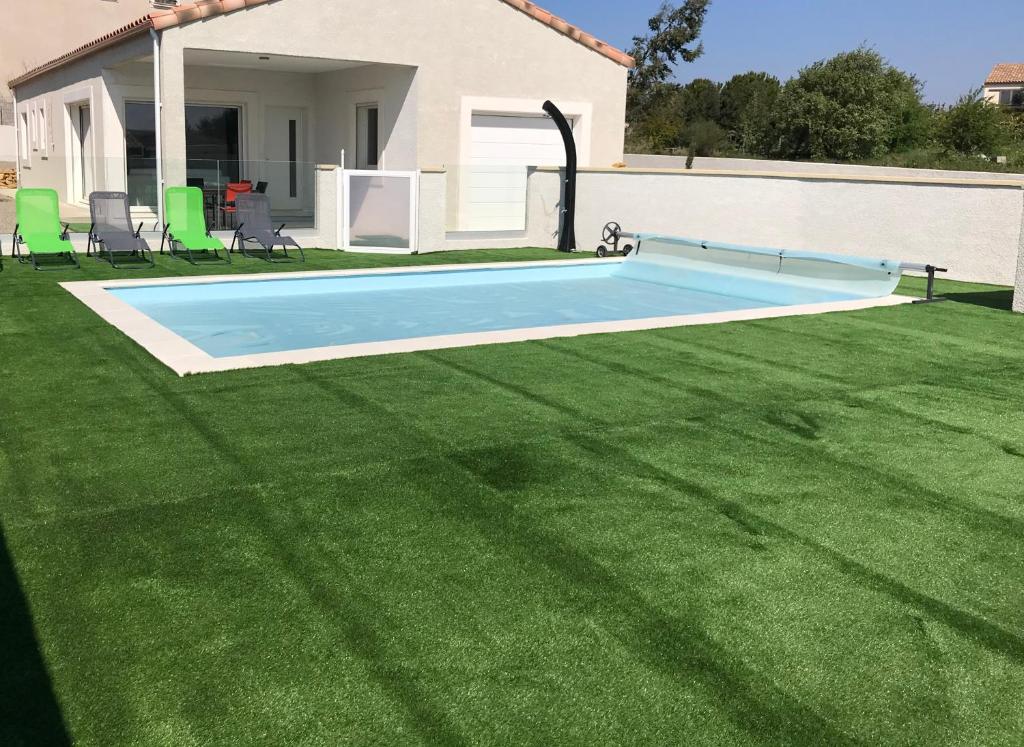 una piscina en un patio con césped verde en Villa les agrumes, en Narbona