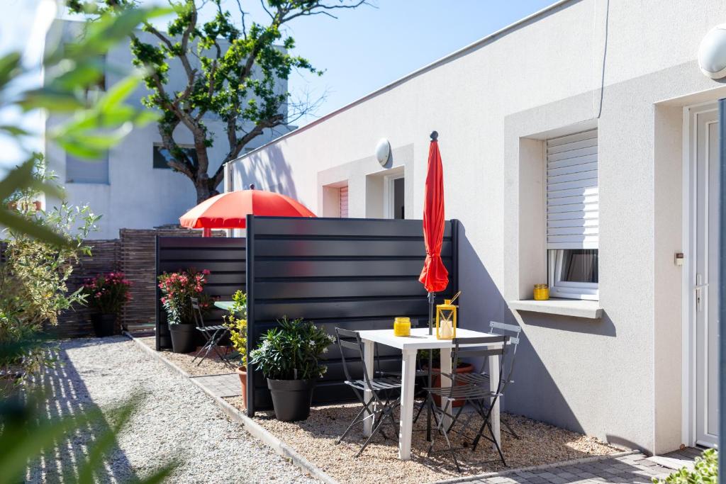 une petite terrasse avec une table et un parasol rouge dans l'établissement La Résidence Salamandre idéal couples & familles grands studios à Saint-Marc-sur-mer à 500m des plages proche de La Baule, à Saint-Nazaire