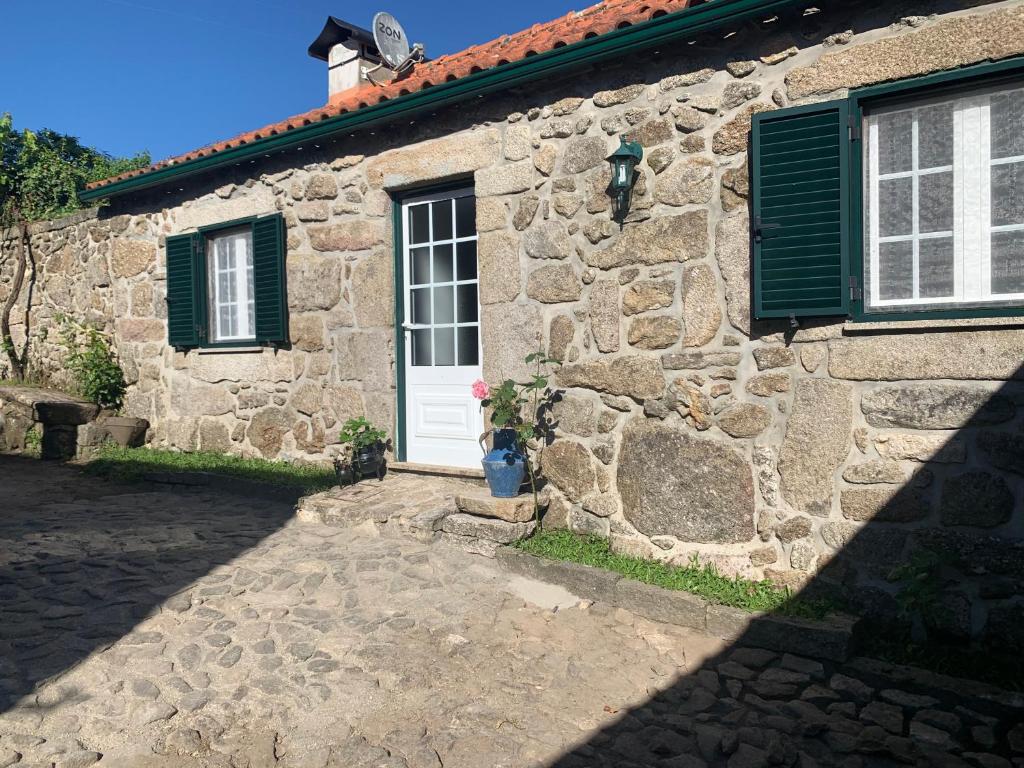 Casa de piedra con puerta blanca y persianas verdes en Casa das Japoneiras, en Paredes de Coura