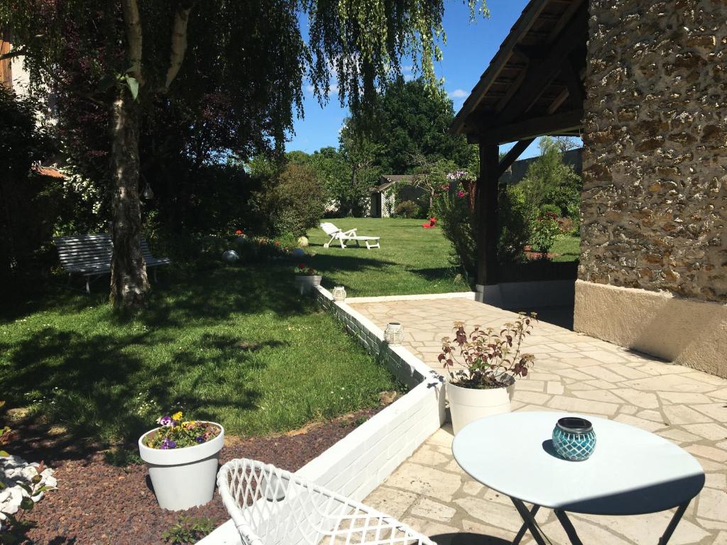 eine Terrasse mit einem Tisch und Stühlen im Hof in der Unterkunft La Chabrière, briarde de charme au calme proche Disneyland in Lumigny