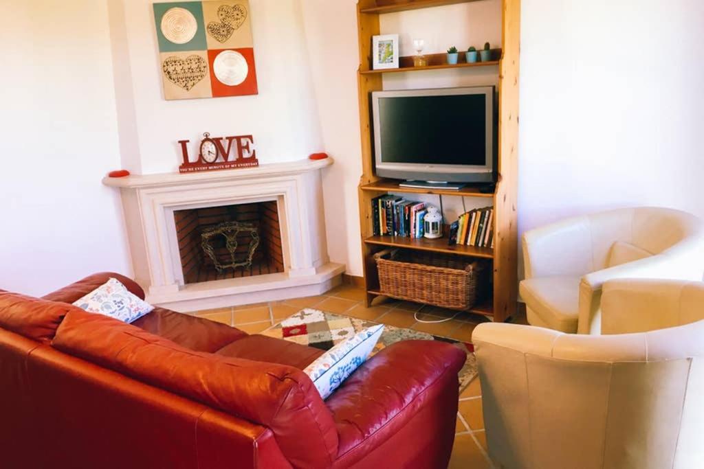 sala de estar con sofá de cuero marrón y TV en Charming Óbidos Townhouse, en Óbidos