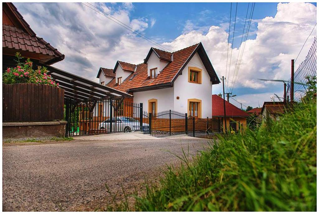 a white house with a brown roof on a street at Chata Margitka in Dúbrava