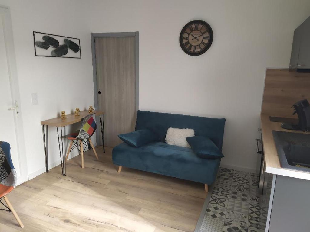 uma sala de estar com um sofá azul e uma mesa em Agréable T2 au calme proche gare em Perpignan