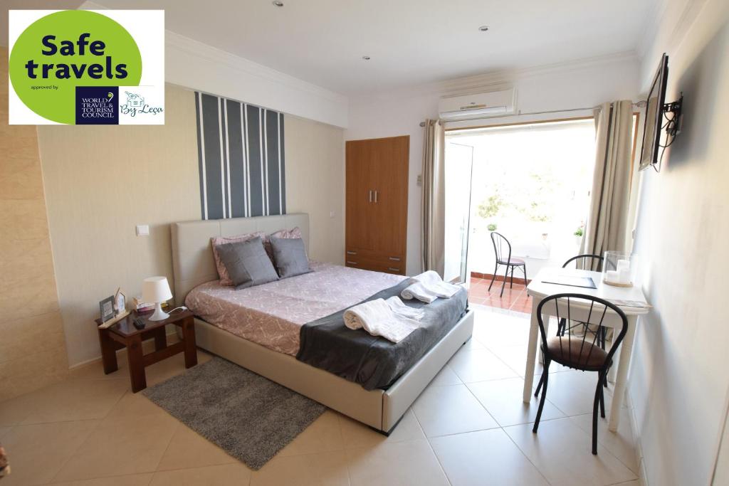 a bedroom with a bed and a table and a balcony at Peneco II in Albufeira