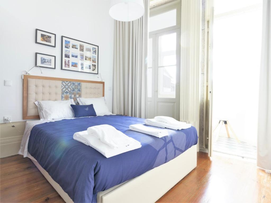 sypialnia z niebieskim łóżkiem i ręcznikami w obiekcie Vanzeleres 285 w Porto