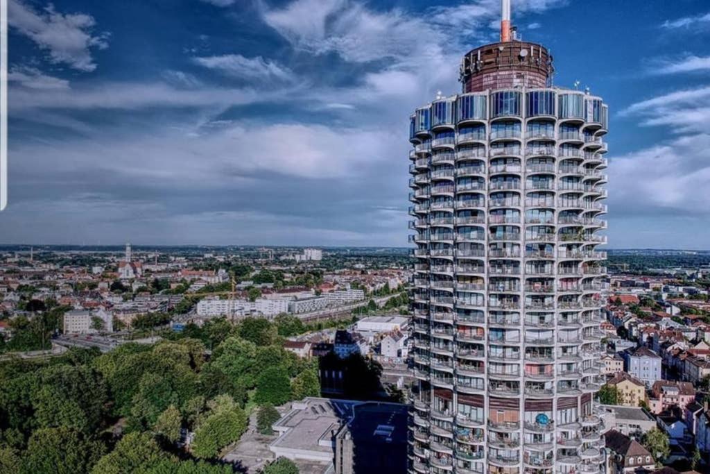 un edificio alto en medio de una ciudad en SUITE-XXI City View Hotelturm Augsburg, en Augsburg