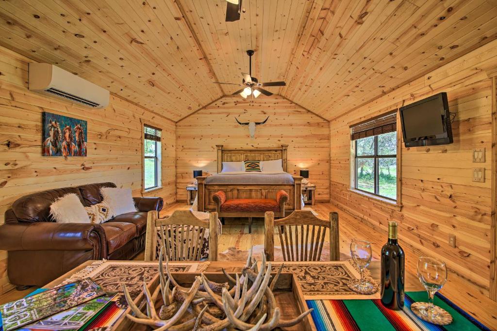 a log cabin living room with a bed and a television at Rustic-Chic Country Cabin - 10 Mi to Main Street! in Fredericksburg