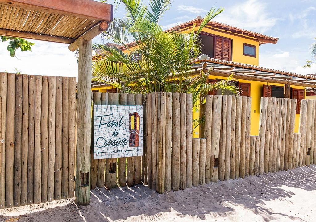 a wooden fence with a sign in front of a house at Pousada Farol de Caraíva in Caraíva