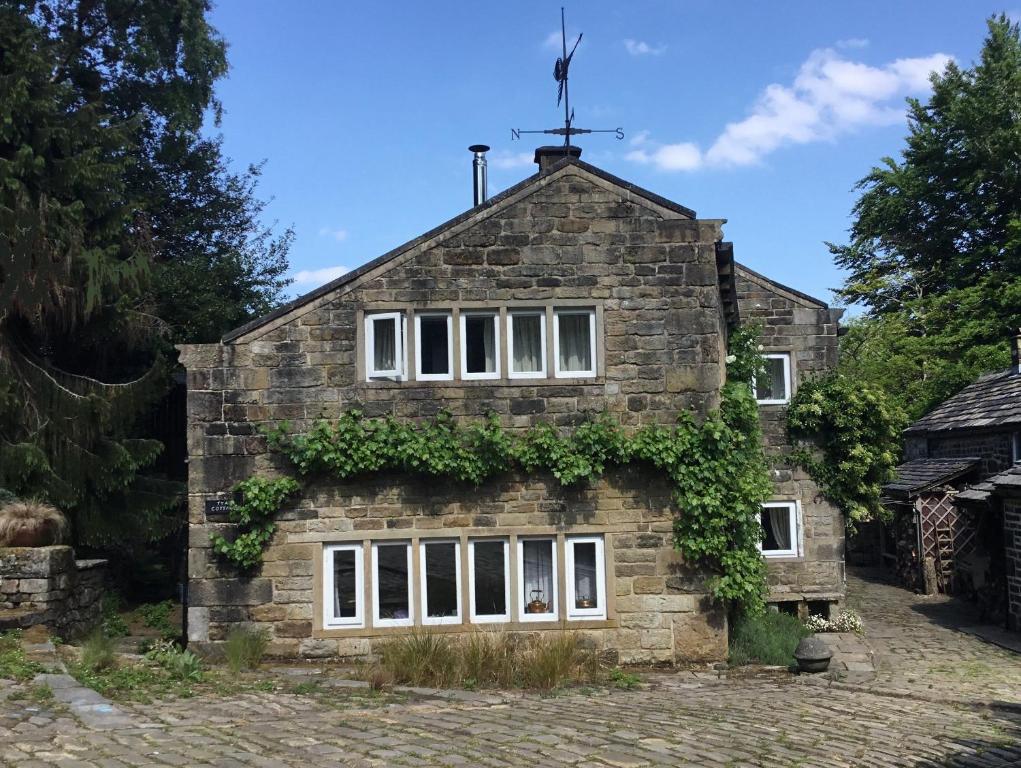 a stone house with ivy on the side of it at Tyas Cottage in Slaithwaite