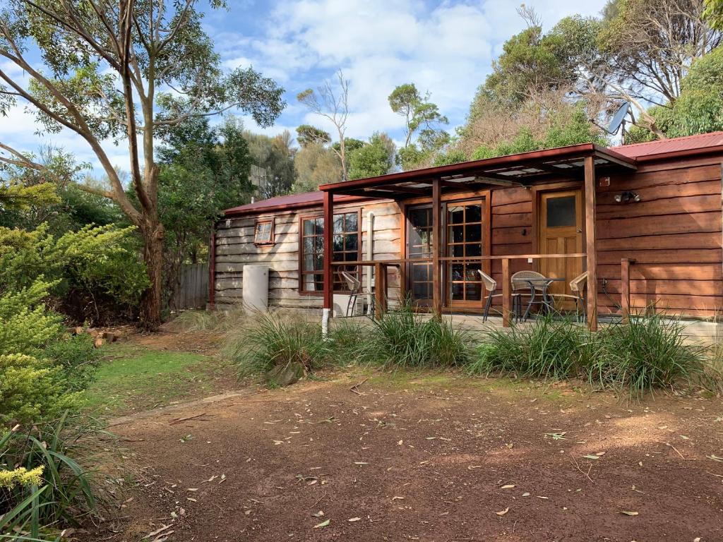 eine kleine Holzhütte mit rotem Dach in der Unterkunft Port Bayou Cottage in Port Campbell