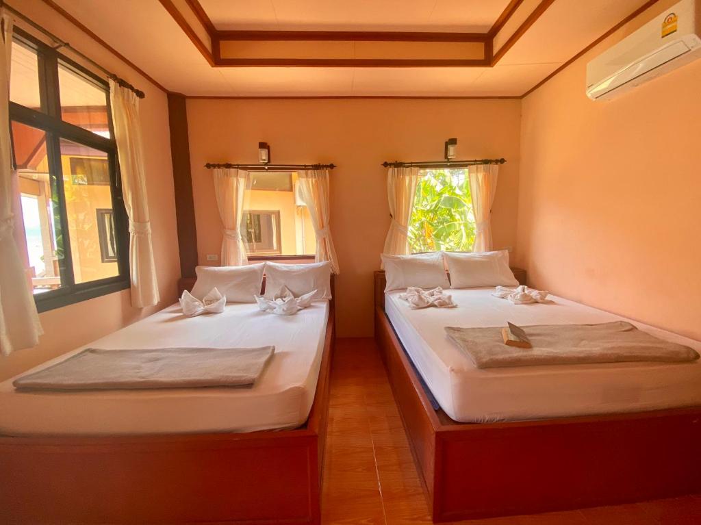 two twin beds in a room with a window at Rainbow Bungalow Haadrin Koh Phangan in Haad Rin