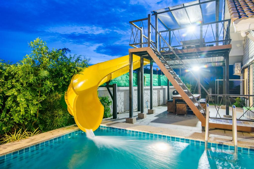 a yellow slide in a swimming pool next to a house at Sierra Pool Villa Hua Hin 102 in Hua Hin