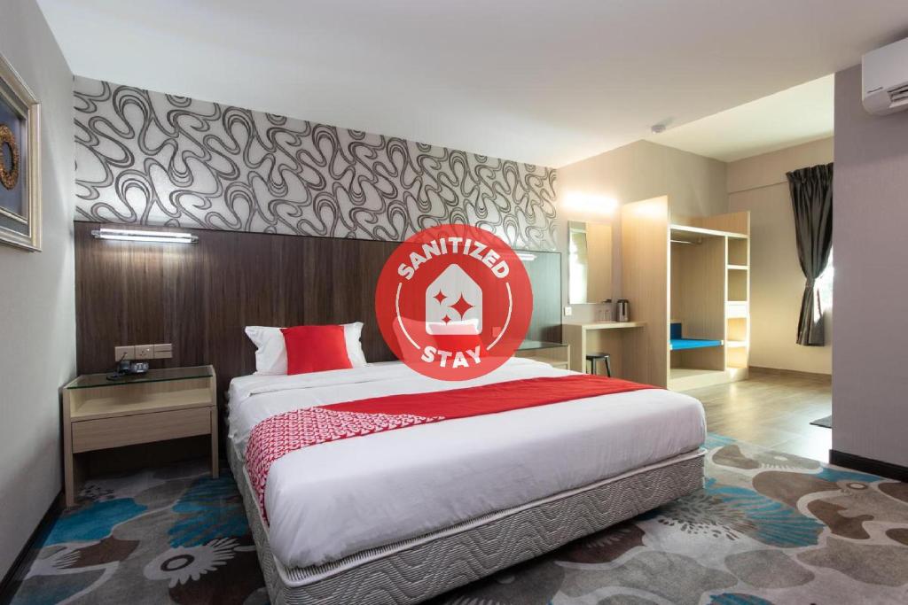 a hotel room with a bed with a red sign on it at Super OYO 89375 Regent Hotel in Keningau