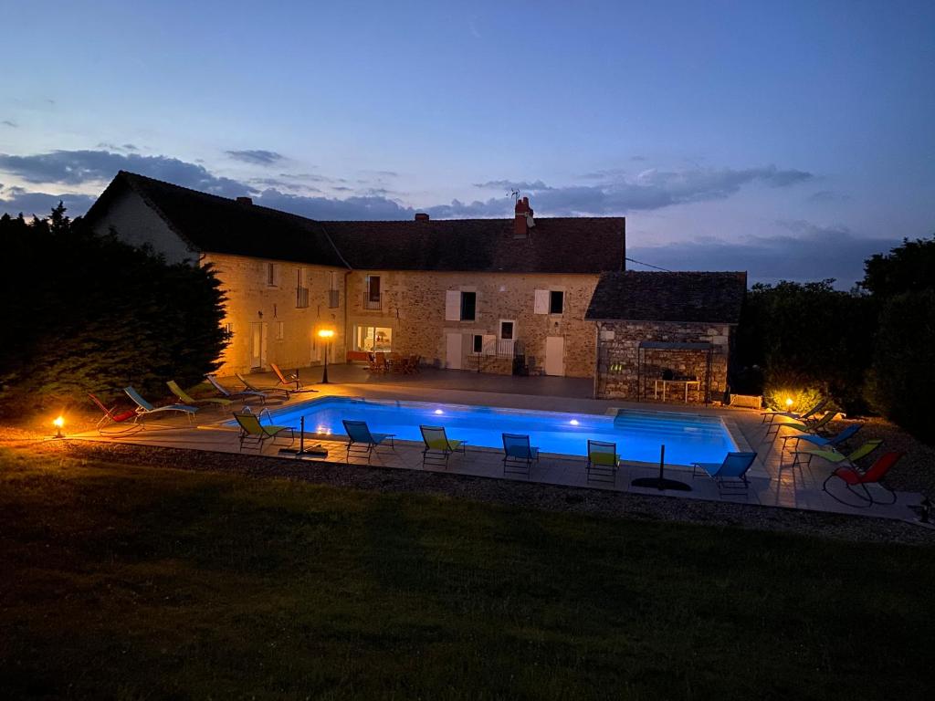 - une piscine en face d'une maison la nuit dans l'établissement Soie Villalunoterie Futuroscope Piscine Spa 6pers, à Oyré